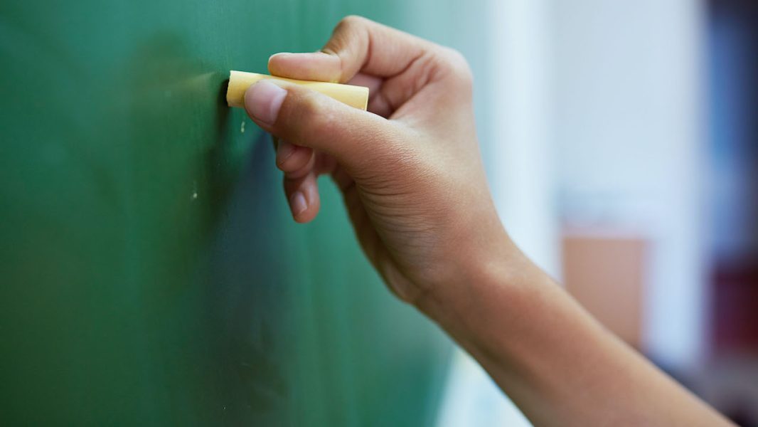 Human hand writing on blackboard